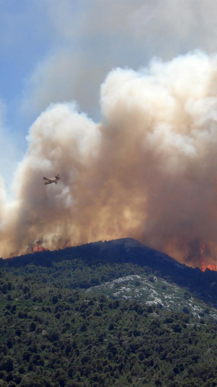 hillside on fire with plume of smoke