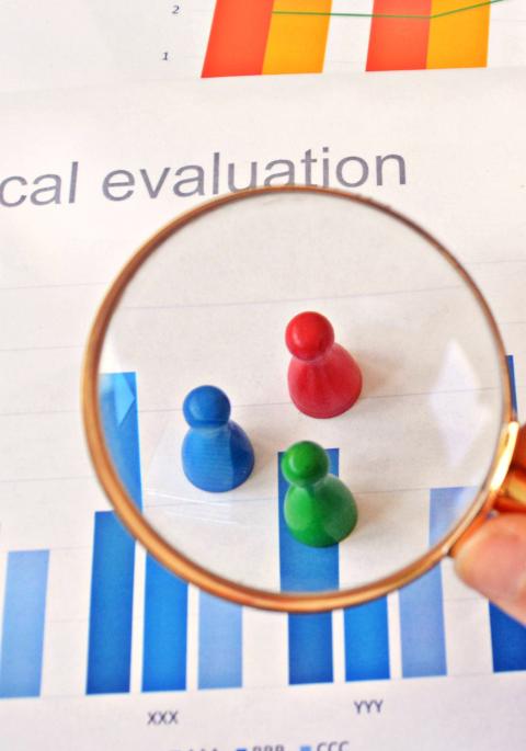 Colored game pieces under magnifying glass with chart background