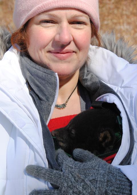 Jennifer with a black bear cub in her coat