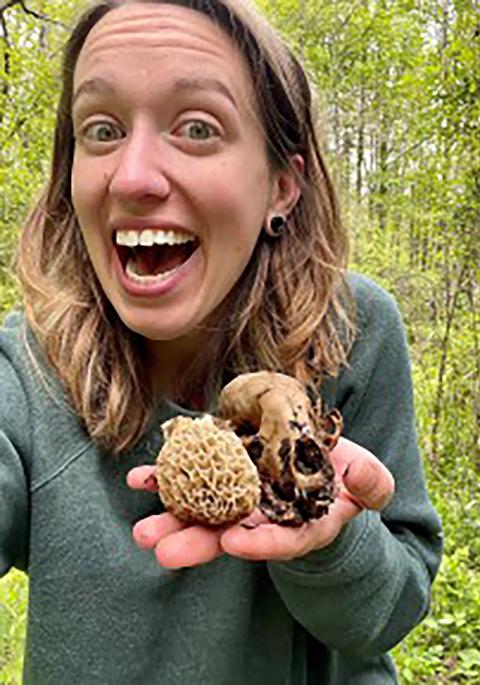 Melissa in the woods holding a skull and mushroom found