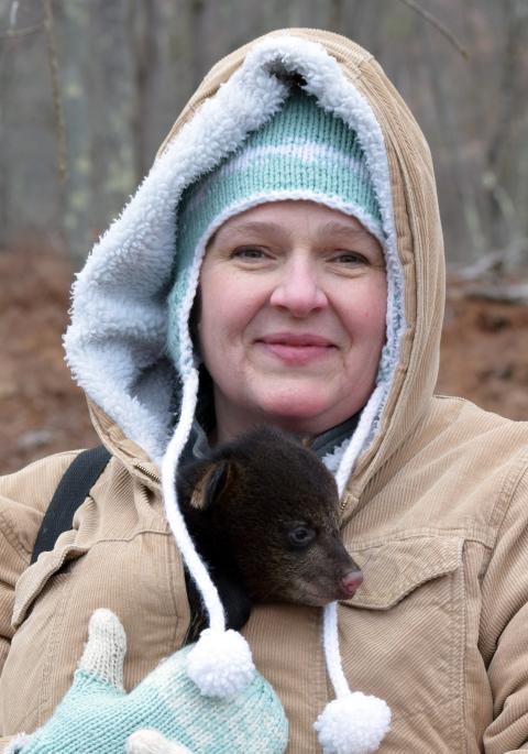 Jennifer with a black bear cub in her coat