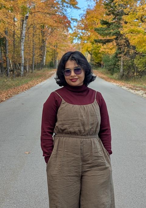 Woman on road with fall foliage in background