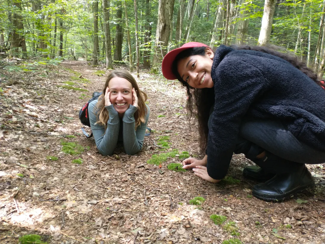 Paula and research specialist Melissa Fadden showing off their newest friend: a tiny juvenile red-spotted newt! He's hiding next to a clump of moss between the two scientists.