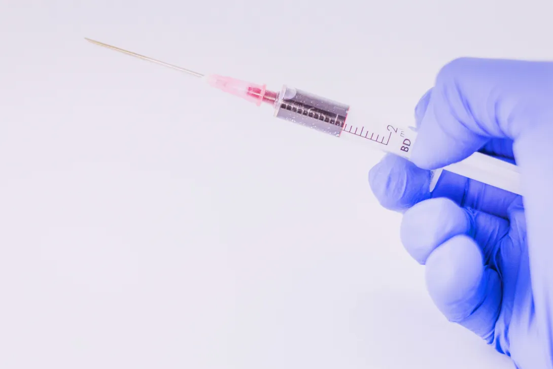 gloved hand holding syringe