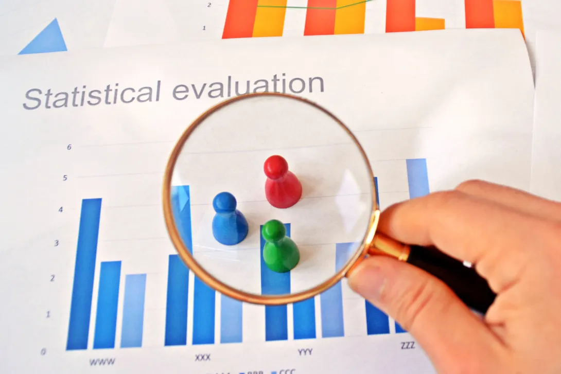 Colored game pieces under magnifying glass with chart background
