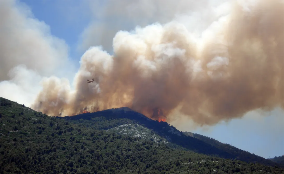 hillside on fire with plume of smoke