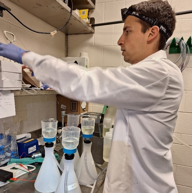 David filtering water for ranavirus eRNA project in the aquatics lab